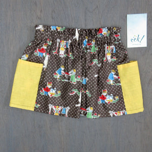 Child's vintage cotton skirt with yellow pockets, fabric has lively scenes of children in blue, yellow, red and green on polka dots,  size 4